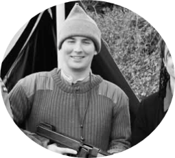 A Picture of the Lead instructor of Battalion Martial Arts Chris May smiling at the camera in Full Commando Uniform holding a Thompson Sub Machine Gun